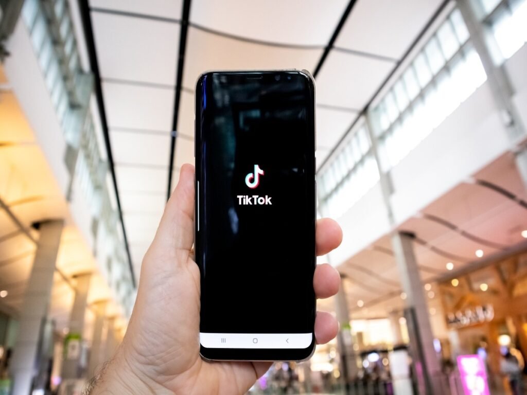 Hand holding a smartphone showing the TikTok app inside a shopping mall