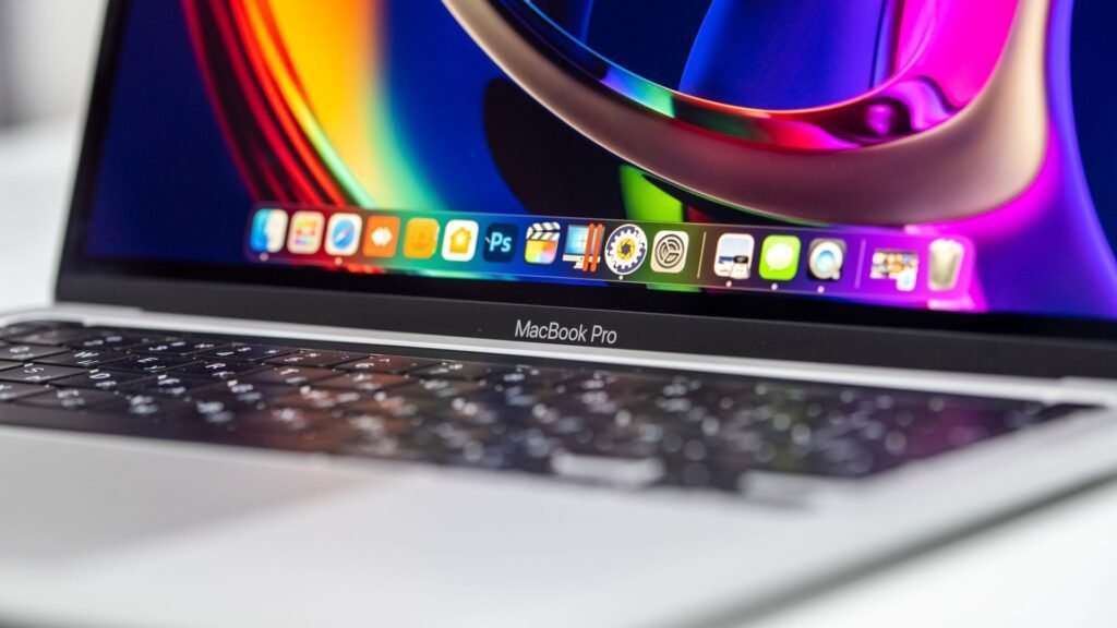 Close-up of a MacBook Pro showing a colorful display, macOS dock, and keyboard