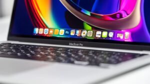 Close-up of a MacBook Pro showing a colorful display, macOS dock, and keyboard