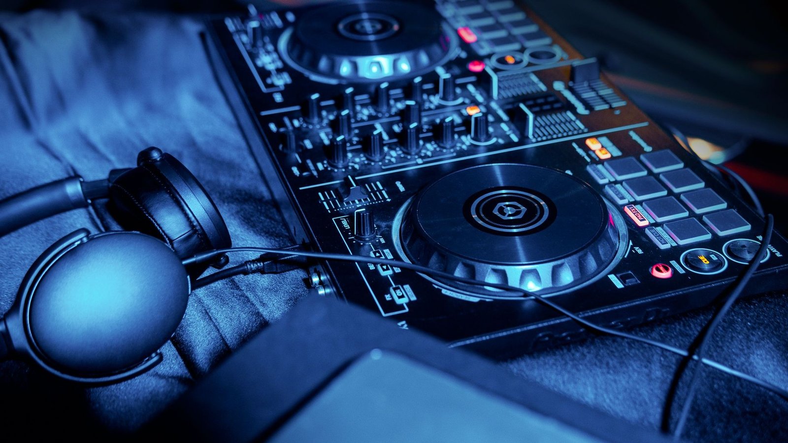 DJ mixer and headphones under blue club lighting